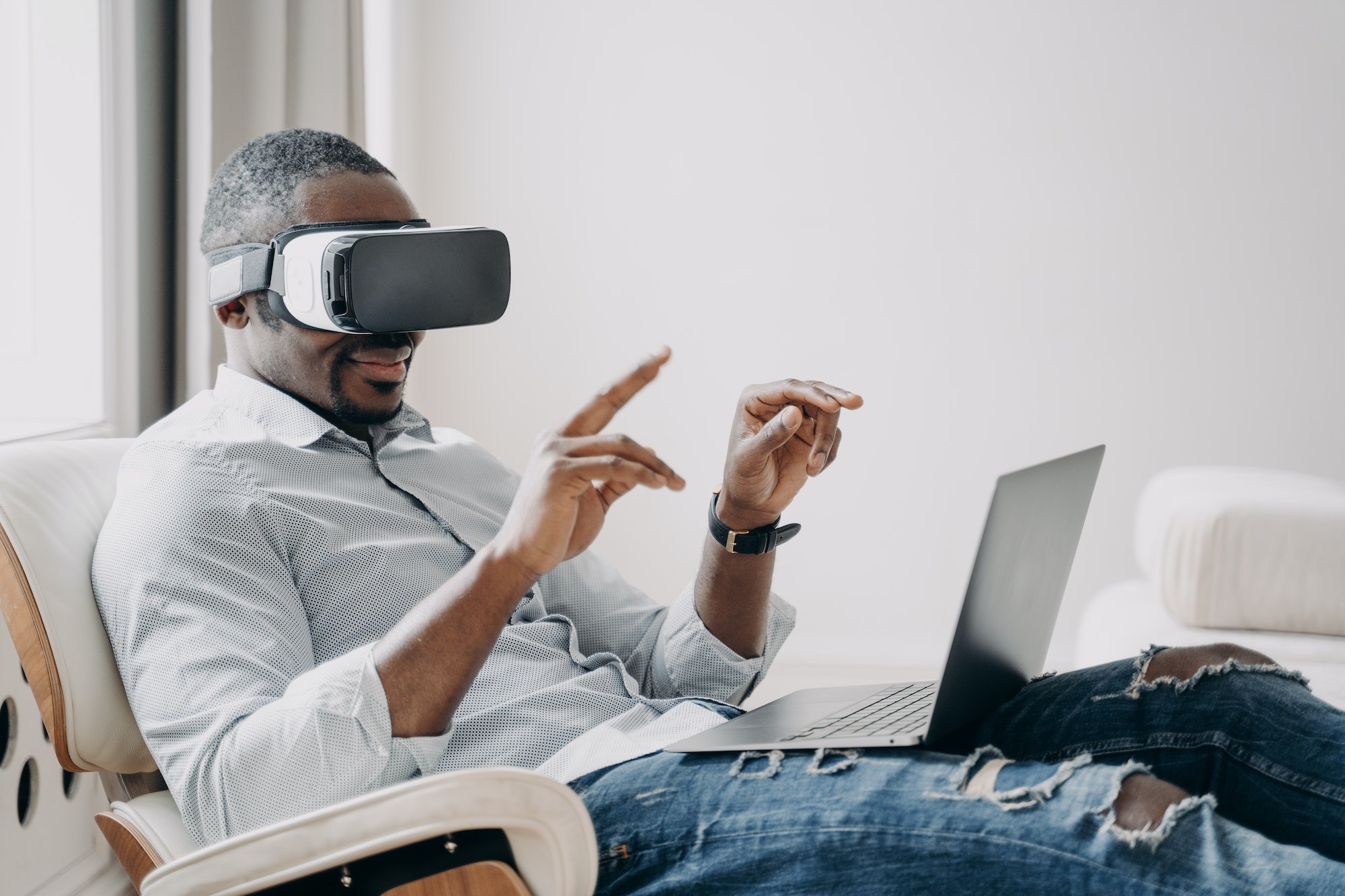 African american businessman in virtual reality glasses sits at laptop. Hightech, future technology